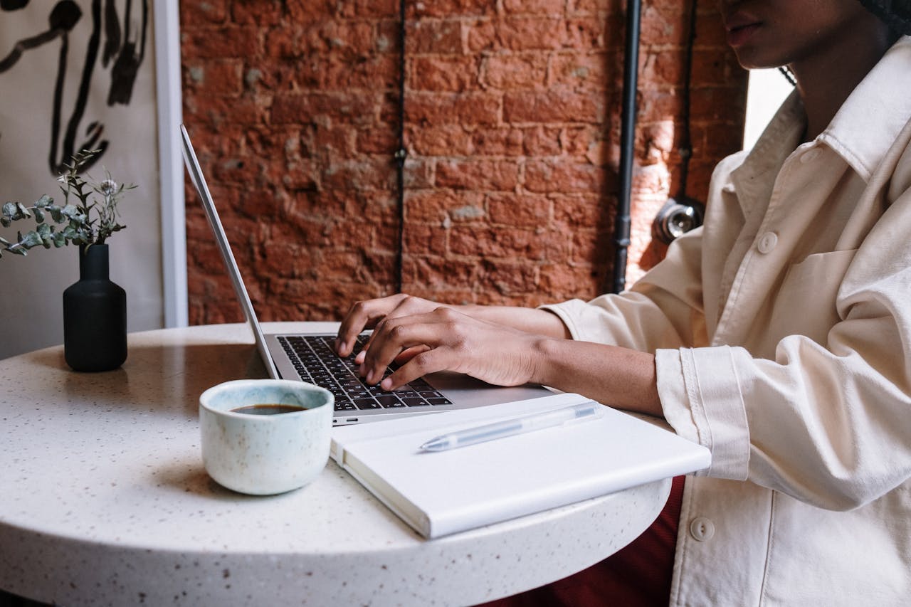 our-mission Woman working on a laptop with coffee in a cozy café, highlighting a productive and modern vibe.